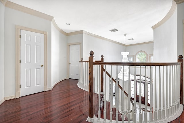 hallway featuring ornamental molding, visible vents, wood finished floors, an upstairs landing, and baseboards