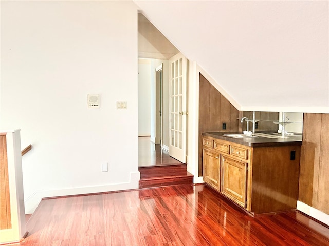 bar featuring baseboards, a sink, and dark wood-type flooring