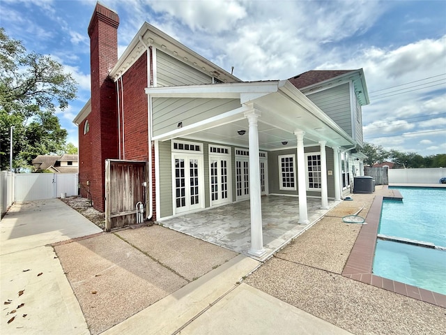 rear view of house featuring a fenced in pool, french doors, central AC, a chimney, and a patio area