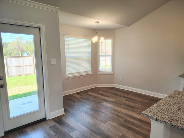 unfurnished dining area featuring an inviting chandelier, baseboards, dark wood-style floors, and a wealth of natural light
