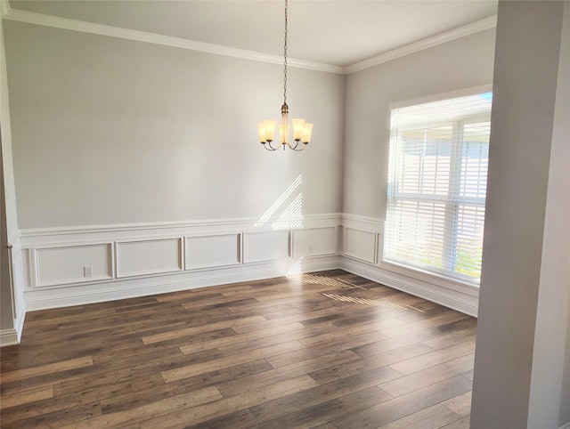 unfurnished dining area with ornamental molding, a notable chandelier, wainscoting, and dark wood finished floors