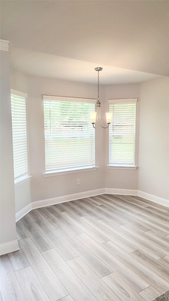 9 Gemstone Ct, Angleton, TX 77515 - unfurnished dining area featuring light wood-type flooring, a chandelier, baseboards, and plenty of natural light
