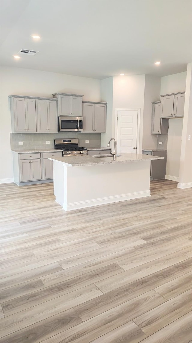 9 Gemstone Ct, Angleton, TX 77515 - kitchen with gray cabinets, appliances with stainless steel finishes, decorative backsplash, recessed lighting, and an island with sink