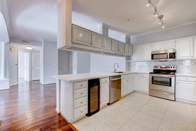 2111 Welch St Unit A107, Houston, TX 77019 - kitchen with appliances with stainless steel finishes, decorative columns, beverage cooler, crown molding, and tasteful backsplash