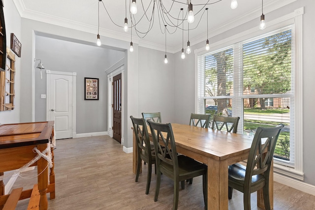 dining area with plenty of natural light, light wood finished floors, baseboards, and crown molding