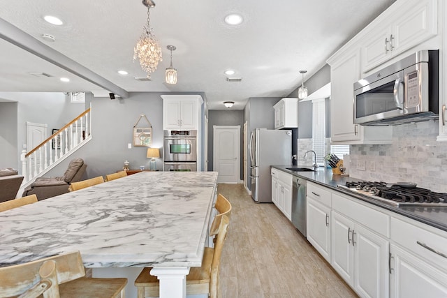kitchen featuring light wood-style flooring, recessed lighting, a sink, stainless steel appliances, and backsplash