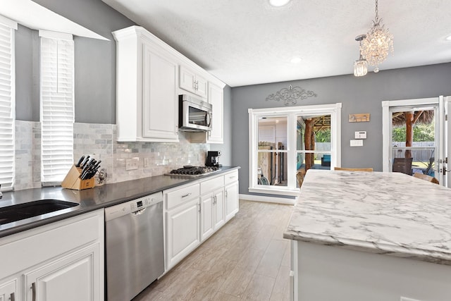 kitchen featuring light wood-type flooring, recessed lighting, white cabinets, decorative backsplash, and appliances with stainless steel finishes