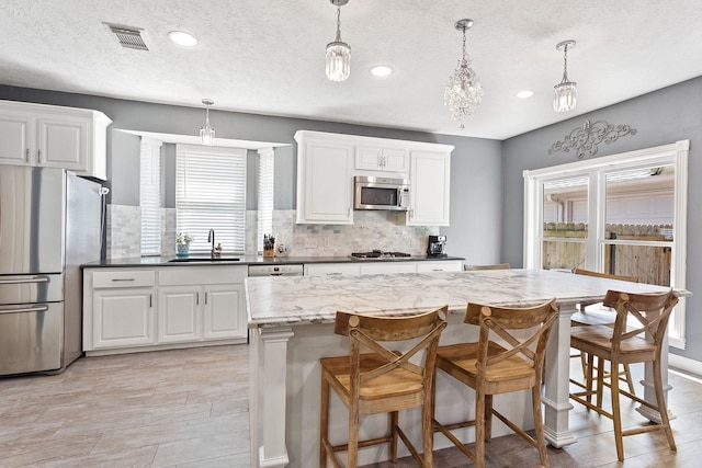 kitchen featuring a sink, recessed lighting, white cabinetry, stainless steel appliances, and backsplash