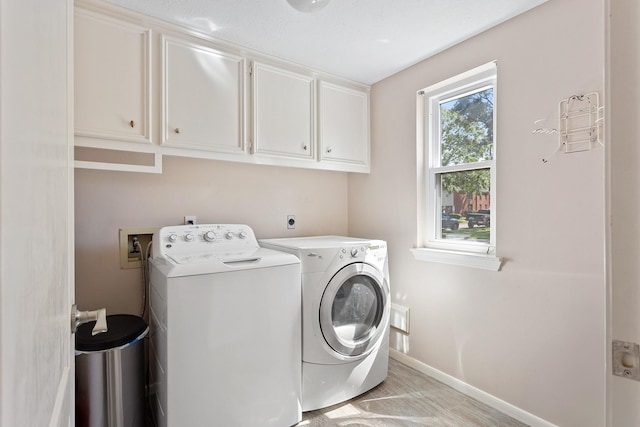 washroom with washing machine and clothes dryer, baseboards, and cabinet space