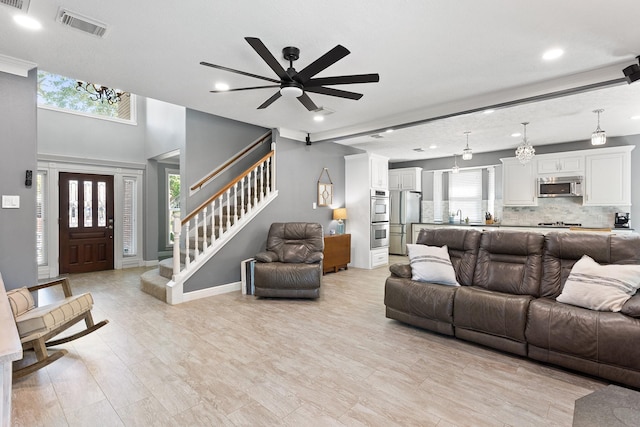 living area with recessed lighting, a wealth of natural light, visible vents, and stairs