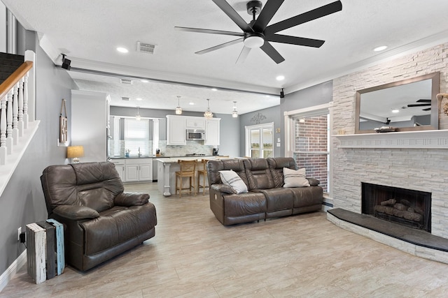 living room with visible vents, ceiling fan, a textured ceiling, a fireplace, and stairs