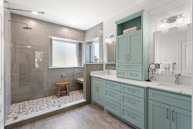 full bath with wood finished floors, double vanity, a sink, and walk in shower