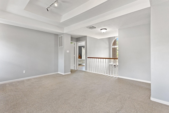 unfurnished room featuring carpet flooring, visible vents, a tray ceiling, and baseboards