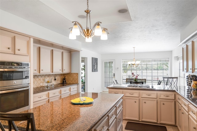 kitchen featuring a peninsula, tasteful backsplash, appliances with stainless steel finishes, and a notable chandelier