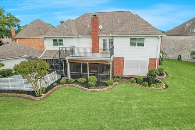 rear view of house with a chimney, roof with shingles, brick siding, a lawn, and a sunroom