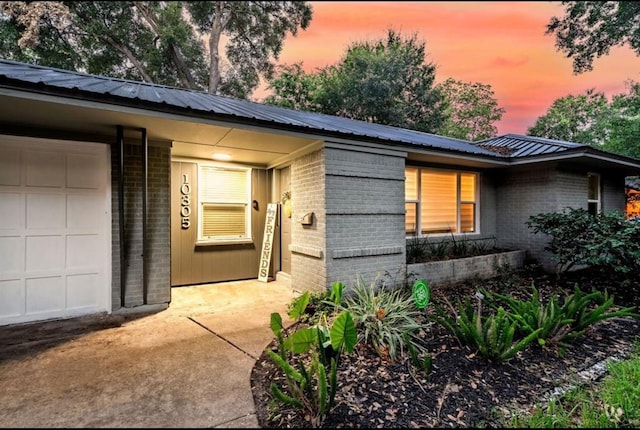 entrance to property with brick siding, metal roof, and an attached garage