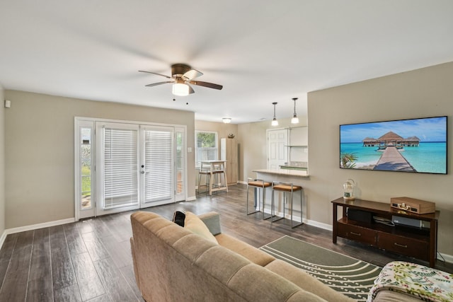 living room featuring baseboards, ceiling fan, and wood finished floors