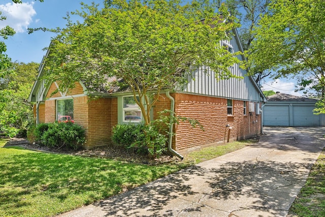 view of property exterior featuring brick siding, a garage, a yard, and an outbuilding
