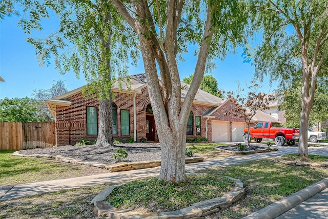 view of front facade with driveway, fence, brick siding, and a garage