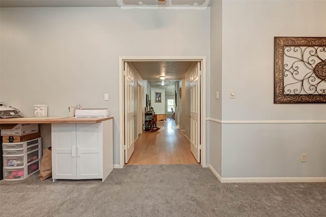 corridor with baseboards and light colored carpet