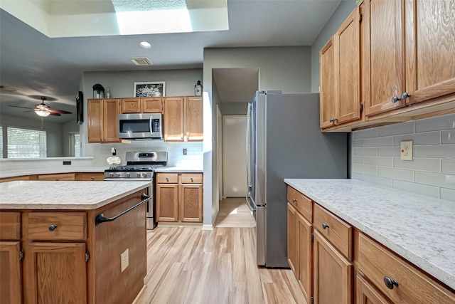 kitchen featuring decorative backsplash, stainless steel appliances, light countertops, light wood-type flooring, and visible vents