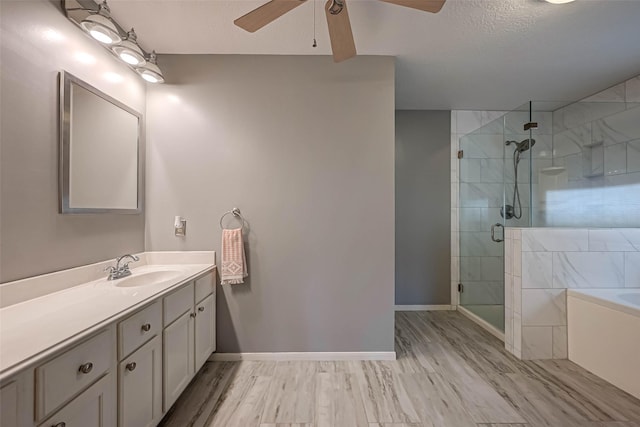 bathroom featuring a shower stall, ceiling fan, a bath, vanity, and baseboards