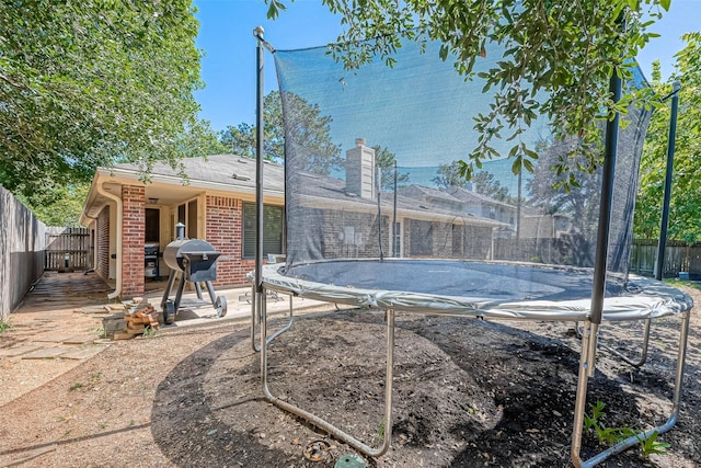 view of swimming pool featuring area for grilling, a fenced backyard, and a trampoline