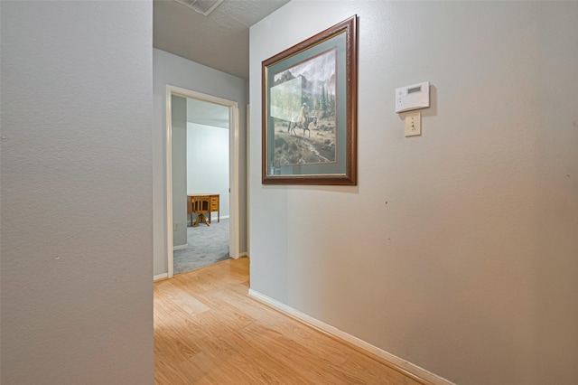 corridor featuring baseboards and light wood-style floors