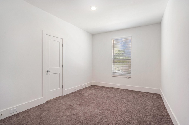 empty room featuring dark carpet, baseboards, and recessed lighting