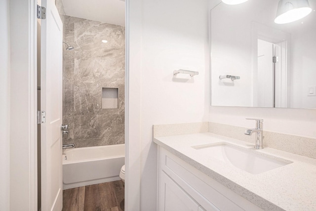 full bathroom featuring toilet, wood finished floors, vanity, and  shower combination