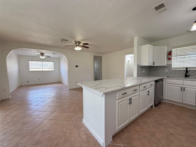 kitchen with a sink, visible vents, ceiling fan, and arched walkways