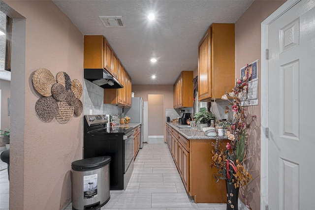 9034 Talton St, Houston, TX 77078 - kitchen featuring visible vents, range with electric stovetop, under cabinet range hood, brown cabinetry, and decorative backsplash