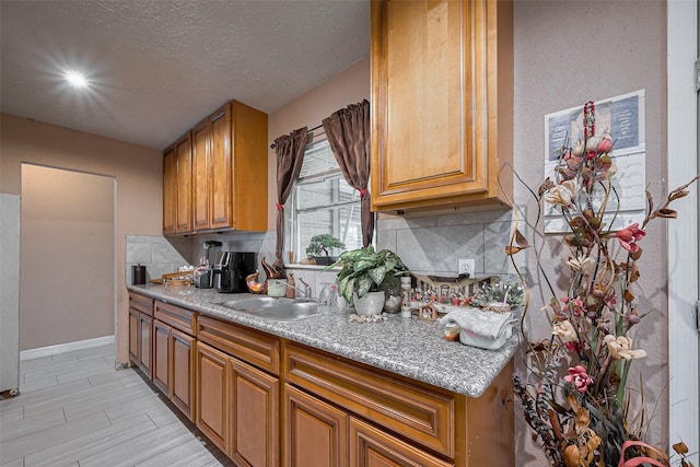 9034 Talton St, Houston, TX 77078 - kitchen featuring brown cabinetry, light countertops, a sink, and backsplash