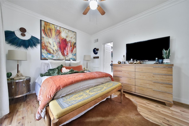 bedroom featuring light wood finished floors, visible vents, crown molding, and ceiling fan