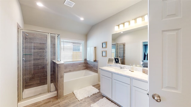 bathroom with vanity, vaulted ceiling, a shower stall, visible vents, and wood finished floors