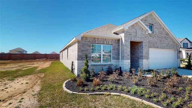 view of front facade with concrete driveway, a front yard, fence, and brick siding