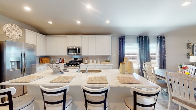 kitchen with recessed lighting, white cabinets, a kitchen island with sink, appliances with stainless steel finishes, and a sink