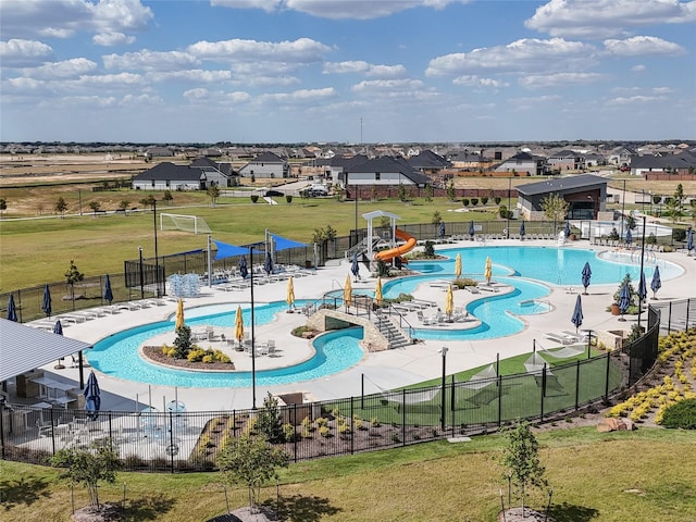 pool with a yard, a water play area, fence, and a water slide