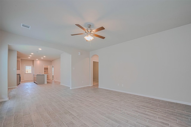 17726 Pamukkale Pl, Tomball, TX 77377 - unfurnished living room with arched walkways, ceiling fan, light wood-type flooring, baseboards, and recessed lighting