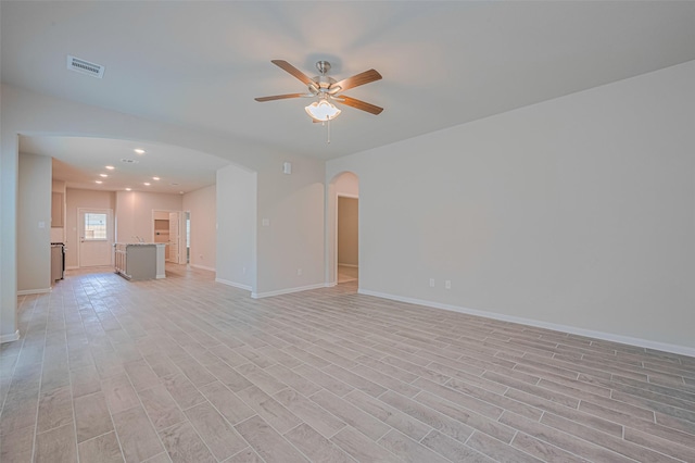 17726 Pamukkale Pl, Tomball, TX 77377 - unfurnished living room featuring arched walkways, a ceiling fan, baseboards, light wood finished floors, and recessed lighting