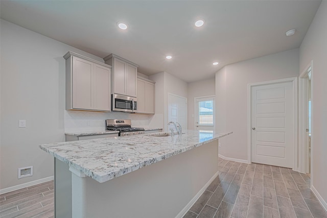 17726 Pamukkale Pl, Tomball, TX 77377 - kitchen with stainless steel appliances, a sink, baseboards, wood tiled floors, and gray cabinets