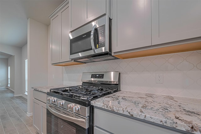 17726 Pamukkale Pl, Tomball, TX 77377 - kitchen with stainless steel appliances, decorative backsplash, light stone countertops, baseboards, and light wood finished floors