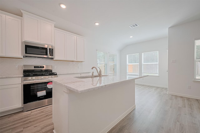 22607 Rising Rosehill Ln, Tomball, TX 77377 - kitchen featuring appliances with stainless steel finishes, a sink, light wood finished floors, backsplash, and light stone countertops