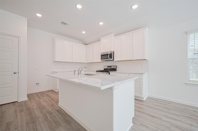 22607 Rising Rosehill Ln, Tomball, TX 77377 - kitchen featuring appliances with stainless steel finishes, a sink, light wood-style floors, an island with sink, and white cabinetry