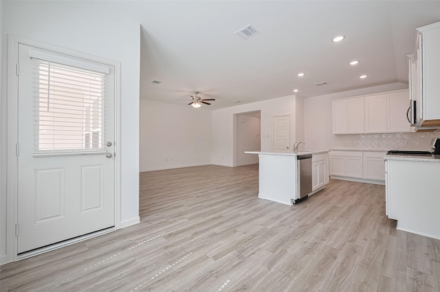 22607 Rising Rosehill Ln, Tomball, TX 77377 - kitchen with appliances with stainless steel finishes, a kitchen island with sink, white cabinetry, decorative backsplash, and light countertops