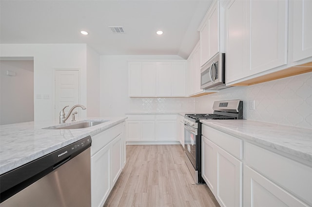 22607 Rising Rosehill Ln, Tomball, TX 77377 - kitchen with stainless steel appliances, a sink, light wood-style flooring, light stone counters, and recessed lighting