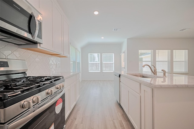 22607 Rising Rosehill Ln, Tomball, TX 77377 - kitchen with appliances with stainless steel finishes, a sink, tasteful backsplash, light wood finished floors, and healthy amount of natural light