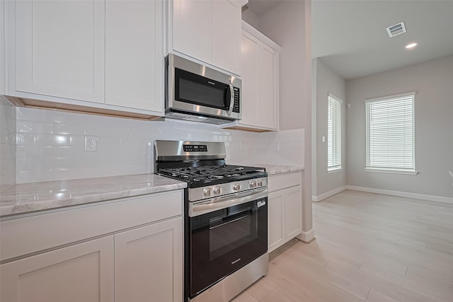 8915 Grovner Pl, Houston, TX 77055 - kitchen featuring stainless steel appliances, decorative backsplash, baseboards, white cabinets, and light stone countertops