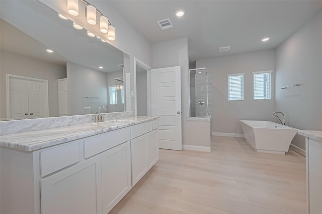 8915 Grovner Pl, Houston, TX 77055 - bathroom featuring a tile shower, vanity, wood finished floors, a soaking tub, and baseboards