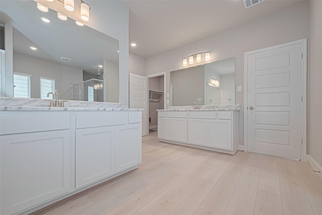 8915 Grovner Pl, Houston, TX 77055 - bathroom with a stall shower, two vanities, wood finished floors, recessed lighting, and a spacious closet